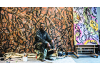 Lonnie Holley sits in front of his work